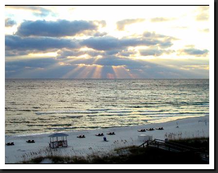 sunset with sun rays over water at panama city beach